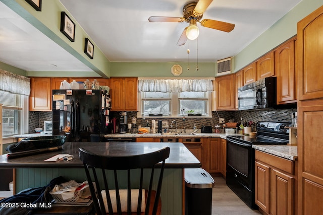 kitchen featuring visible vents, brown cabinetry, a sink, black appliances, and backsplash