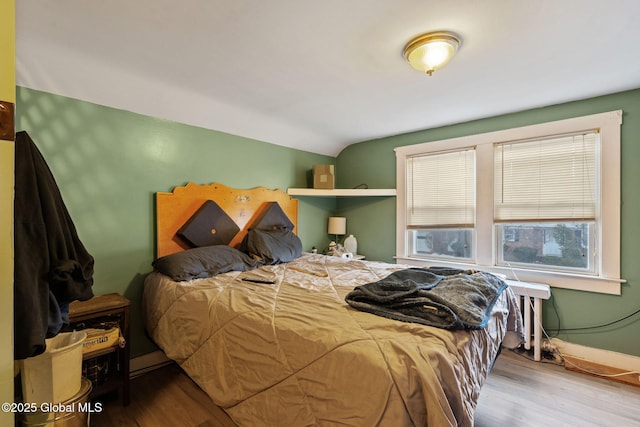 bedroom with vaulted ceiling, baseboards, and wood finished floors