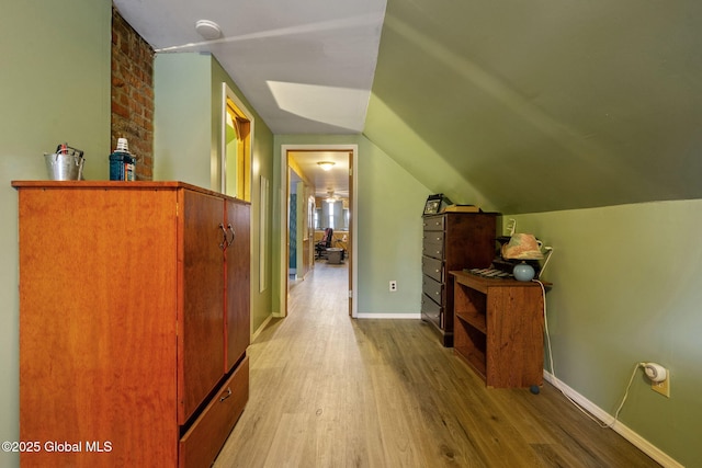 corridor with lofted ceiling, baseboards, and wood finished floors