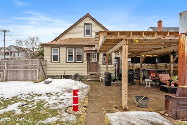 rear view of property featuring entry steps, a patio area, a shingled roof, and fence