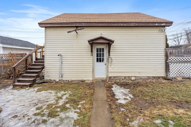 rear view of property featuring fence and roof with shingles