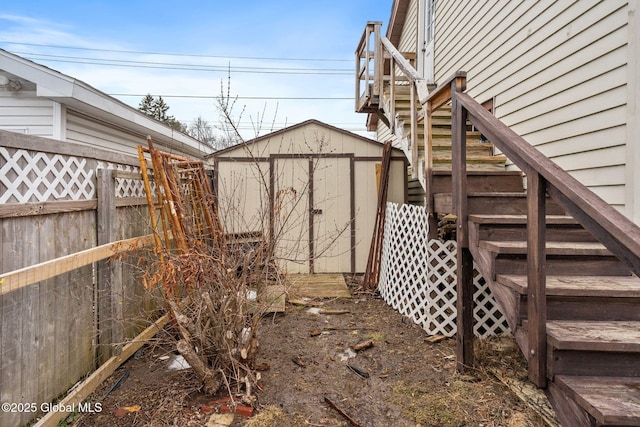 exterior space featuring a storage shed, an outdoor structure, fence, and stairs