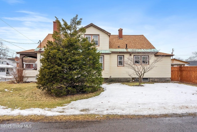 view of home's exterior with metal roof, a chimney, and fence