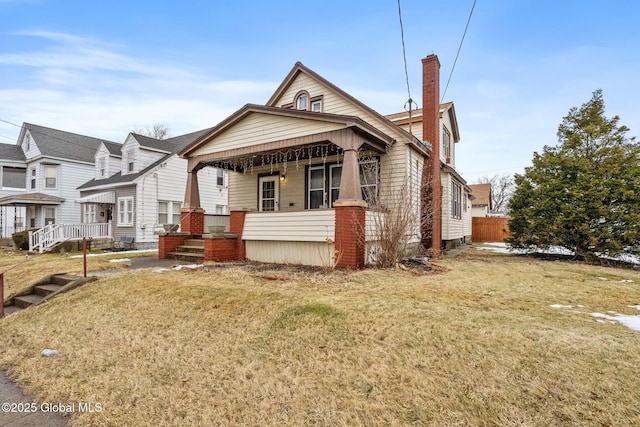 view of front of house featuring a porch, a chimney, and a front lawn