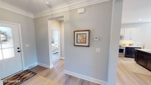 foyer entrance with crown molding, light wood-style flooring, and baseboards