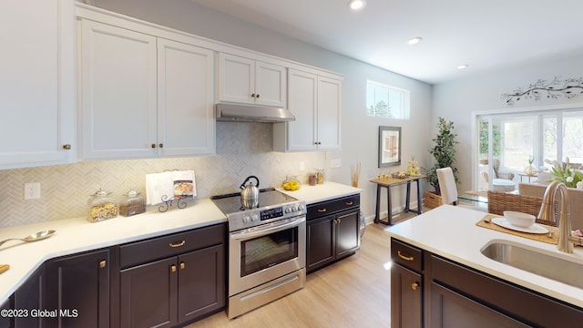 kitchen with under cabinet range hood, a sink, light countertops, and stainless steel range with electric cooktop