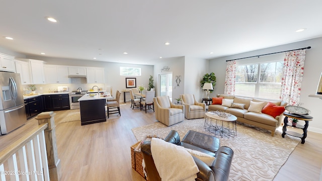 living area featuring baseboards, light wood-type flooring, and recessed lighting