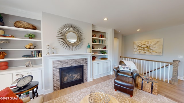 living area featuring wood finished floors, an upstairs landing, built in shelves, a fireplace, and recessed lighting