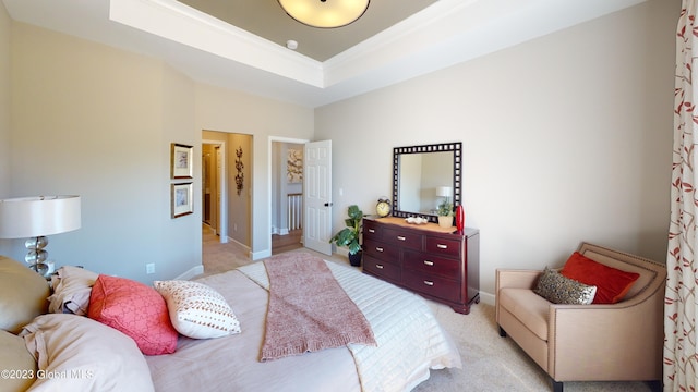 bedroom with a tray ceiling, light carpet, crown molding, and baseboards