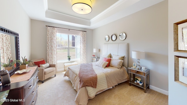 bedroom with crown molding, a tray ceiling, baseboards, and light colored carpet