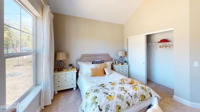 bedroom with lofted ceiling, a closet, light carpet, and baseboards