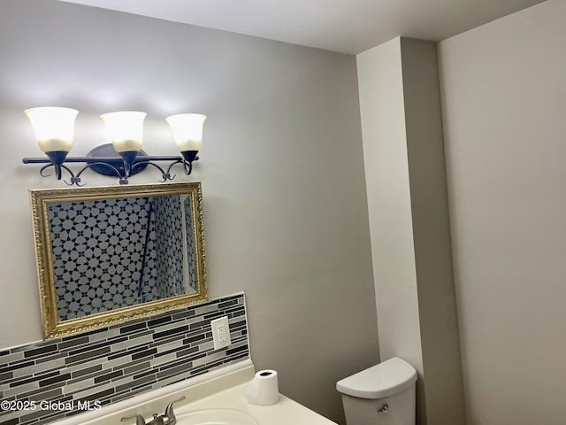 half bathroom featuring toilet, a sink, decorative backsplash, and a notable chandelier