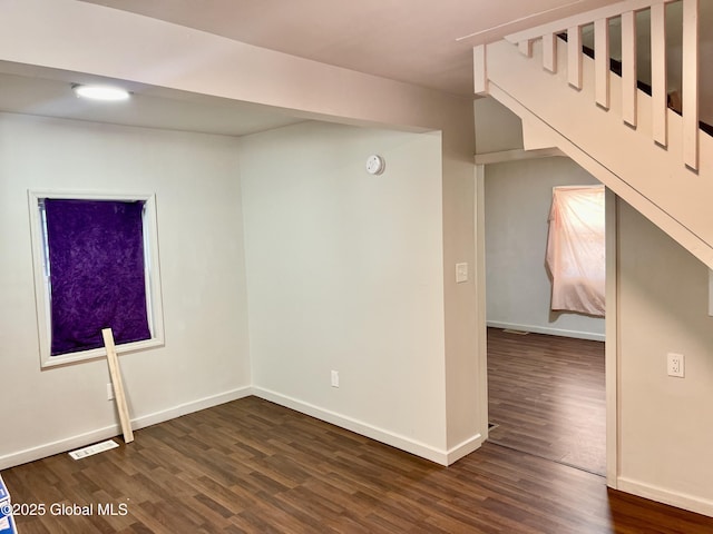 unfurnished room featuring dark wood-type flooring, visible vents, and baseboards