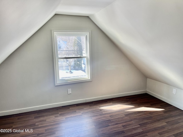 bonus room with baseboards, vaulted ceiling, and dark wood-style flooring