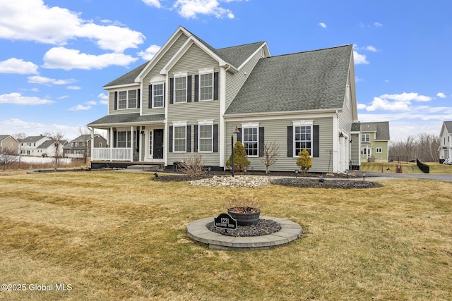 view of front of house featuring a porch, an outdoor fire pit, a front yard, and a shingled roof