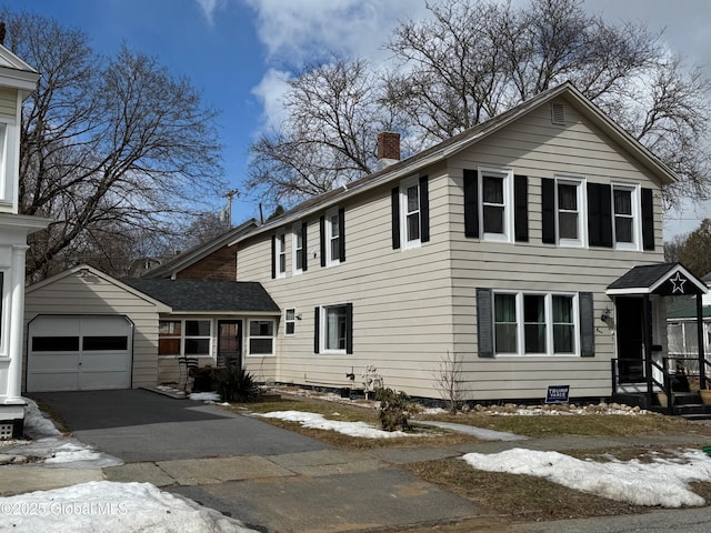 view of front of property featuring driveway, an attached garage, and a chimney