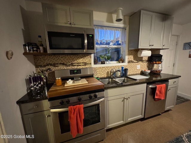 kitchen with stainless steel appliances, backsplash, white cabinets, a sink, and baseboards