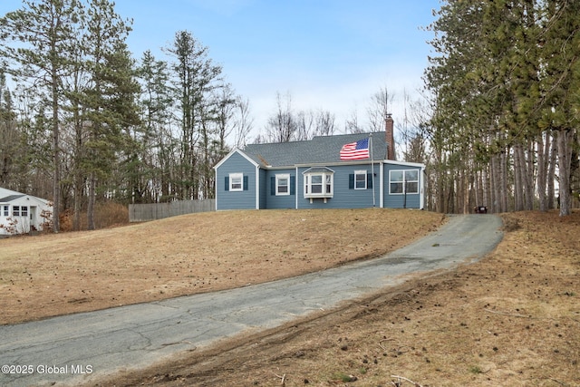 view of front of property featuring a shingled roof, a chimney, and fence