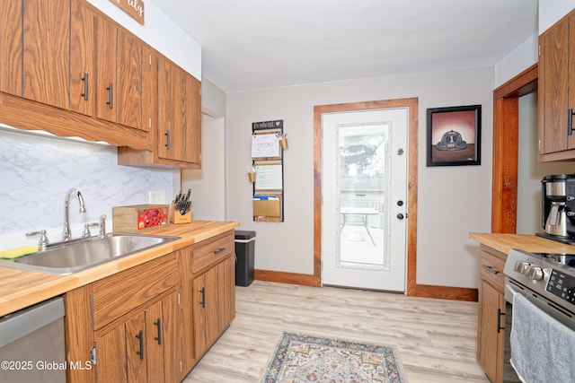 kitchen with butcher block counters, appliances with stainless steel finishes, tasteful backsplash, and a sink