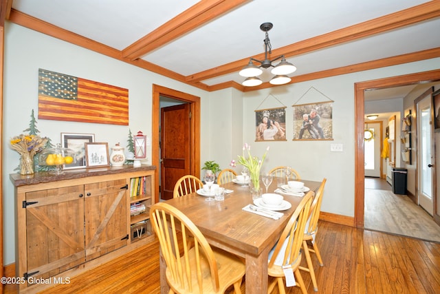 dining area featuring a chandelier, beam ceiling, baseboards, and hardwood / wood-style floors