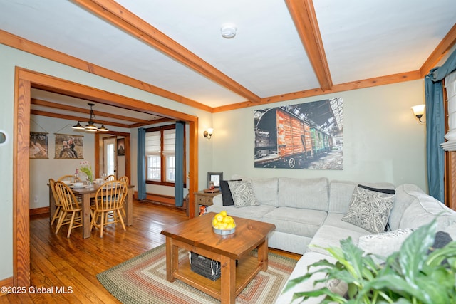 living room featuring beamed ceiling, wood-type flooring, and baseboards