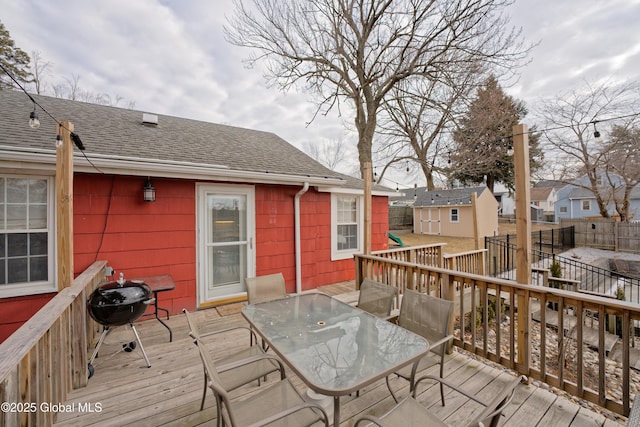 wooden deck with fence, an outdoor structure, and outdoor dining space