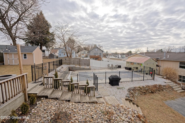 view of yard featuring a fenced backyard, an outdoor structure, a wooden deck, a residential view, and a patio area