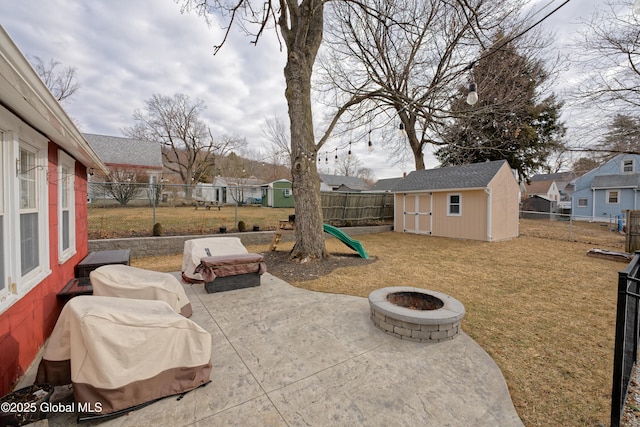 view of jungle gym with a patio, a storage shed, a fenced backyard, an outdoor structure, and a fire pit