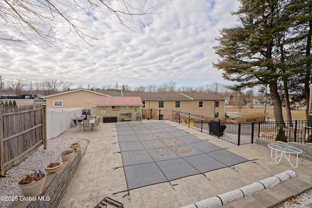 community pool with a patio area and a fenced backyard