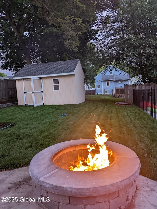 exterior space featuring an outbuilding, a fenced backyard, an outdoor fire pit, and a storage unit