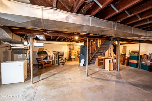 unfinished basement with stairs and fridge