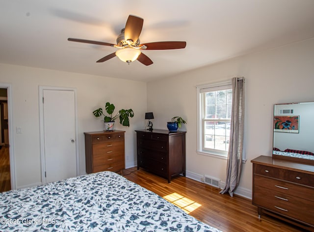 bedroom featuring visible vents, ceiling fan, baseboards, and wood finished floors