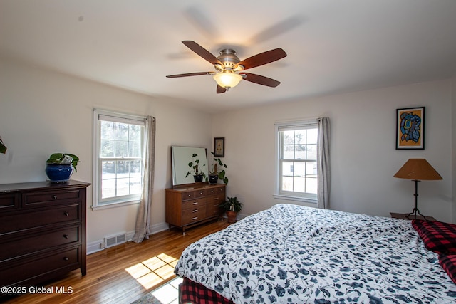 bedroom with visible vents, baseboards, ceiling fan, and wood finished floors