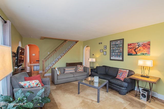 living room with stairs, wood finished floors, arched walkways, and baseboards