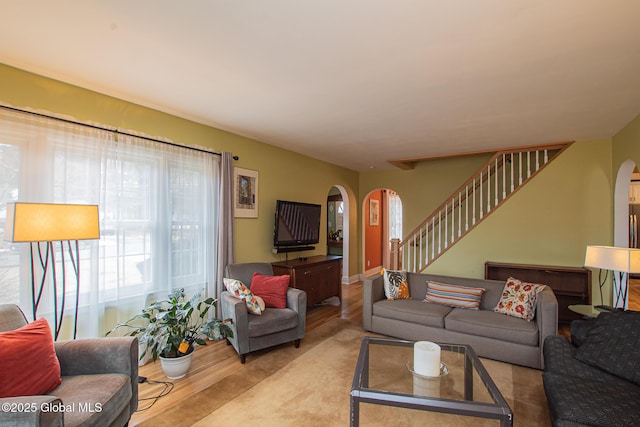 living room with stairway, arched walkways, and wood finished floors