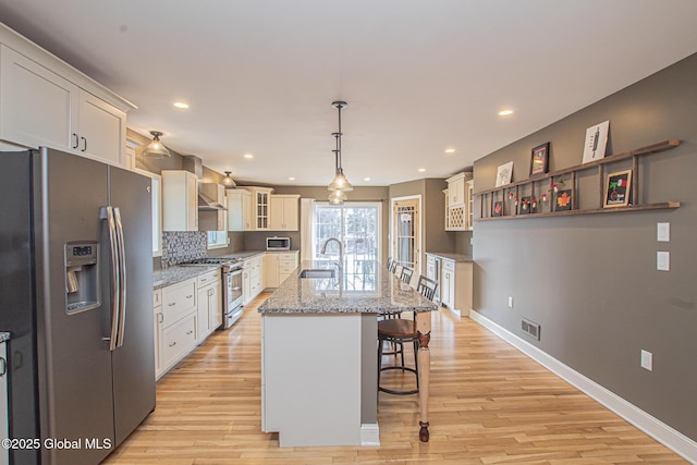 kitchen featuring light wood finished floors, visible vents, a breakfast bar area, appliances with stainless steel finishes, and a sink