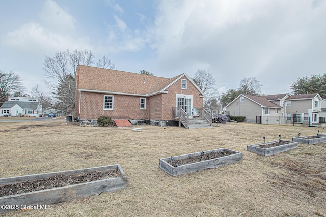 back of house with brick siding, a residential view, a yard, and a vegetable garden