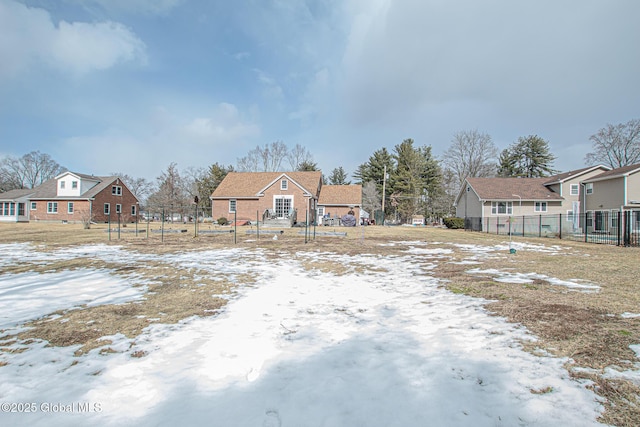 yard covered in snow with fence and a residential view