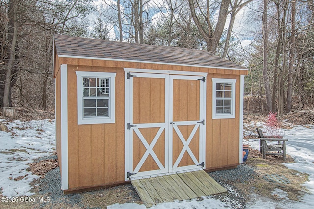 snow covered structure featuring an outdoor structure and a shed