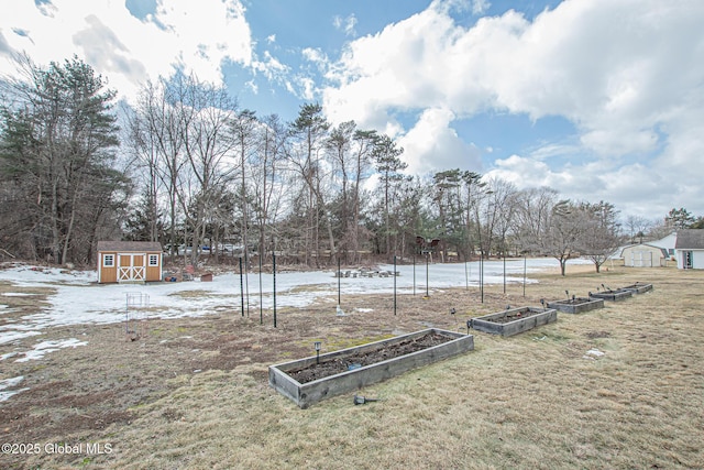 yard layered in snow featuring an outdoor structure, a garden, and a shed