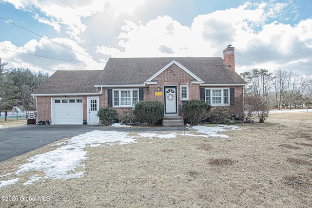 view of front of property featuring driveway, a shingled roof, a garage, brick siding, and a chimney