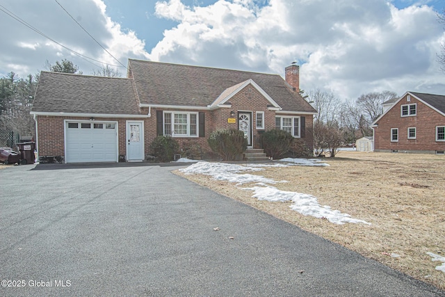 view of front of property featuring roof with shingles, driveway, a chimney, a garage, and brick siding