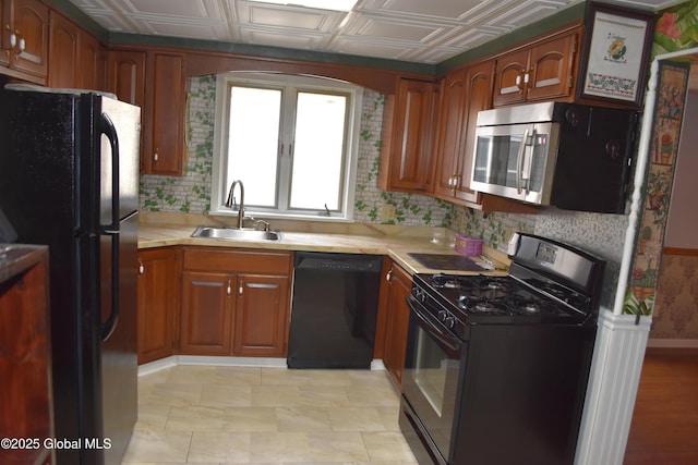 kitchen with brown cabinets, black appliances, a sink, an ornate ceiling, and light countertops