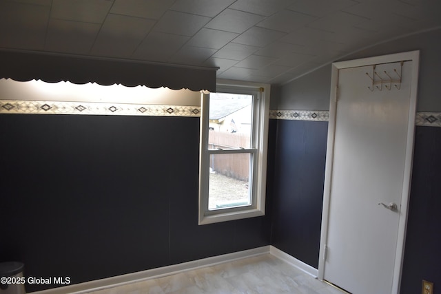 unfurnished room featuring lofted ceiling and baseboards