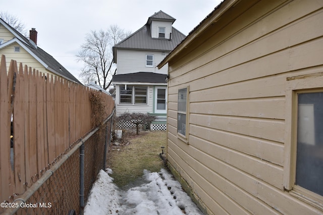 view of side of home featuring metal roof and fence