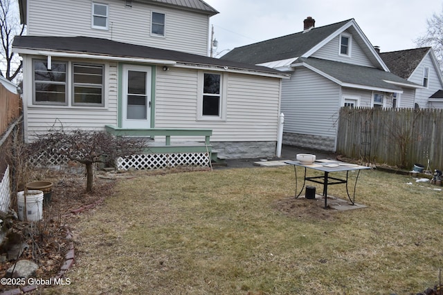 rear view of property featuring a lawn and fence