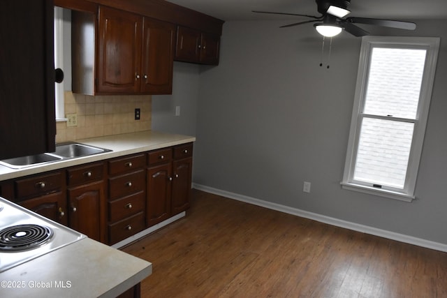 kitchen featuring a sink, tasteful backsplash, dark wood finished floors, and light countertops