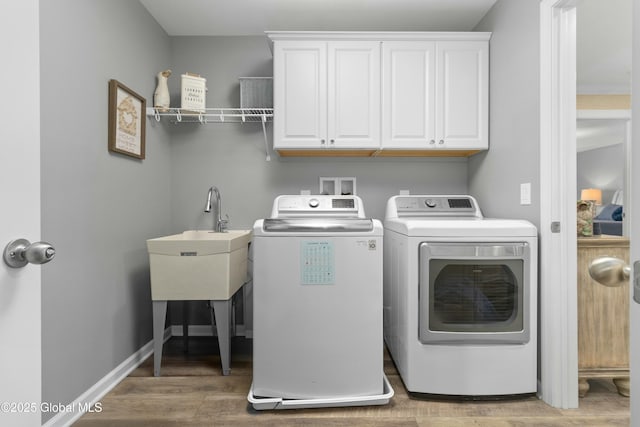 laundry area with cabinet space, washer and dryer, baseboards, and wood finished floors