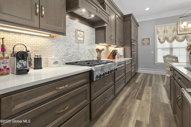 kitchen with dark wood-style flooring, ornamental molding, decorative backsplash, stainless steel appliances, and custom range hood