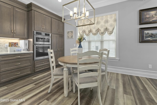 dining space with dark wood-style floors, a chandelier, baseboards, and ornamental molding